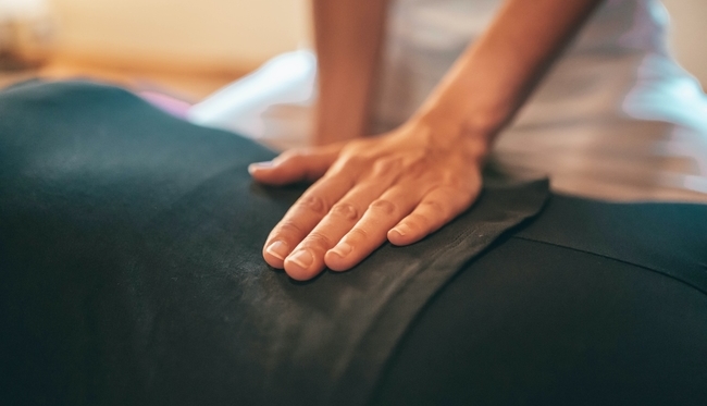 A hand massaging the lower back of a patient